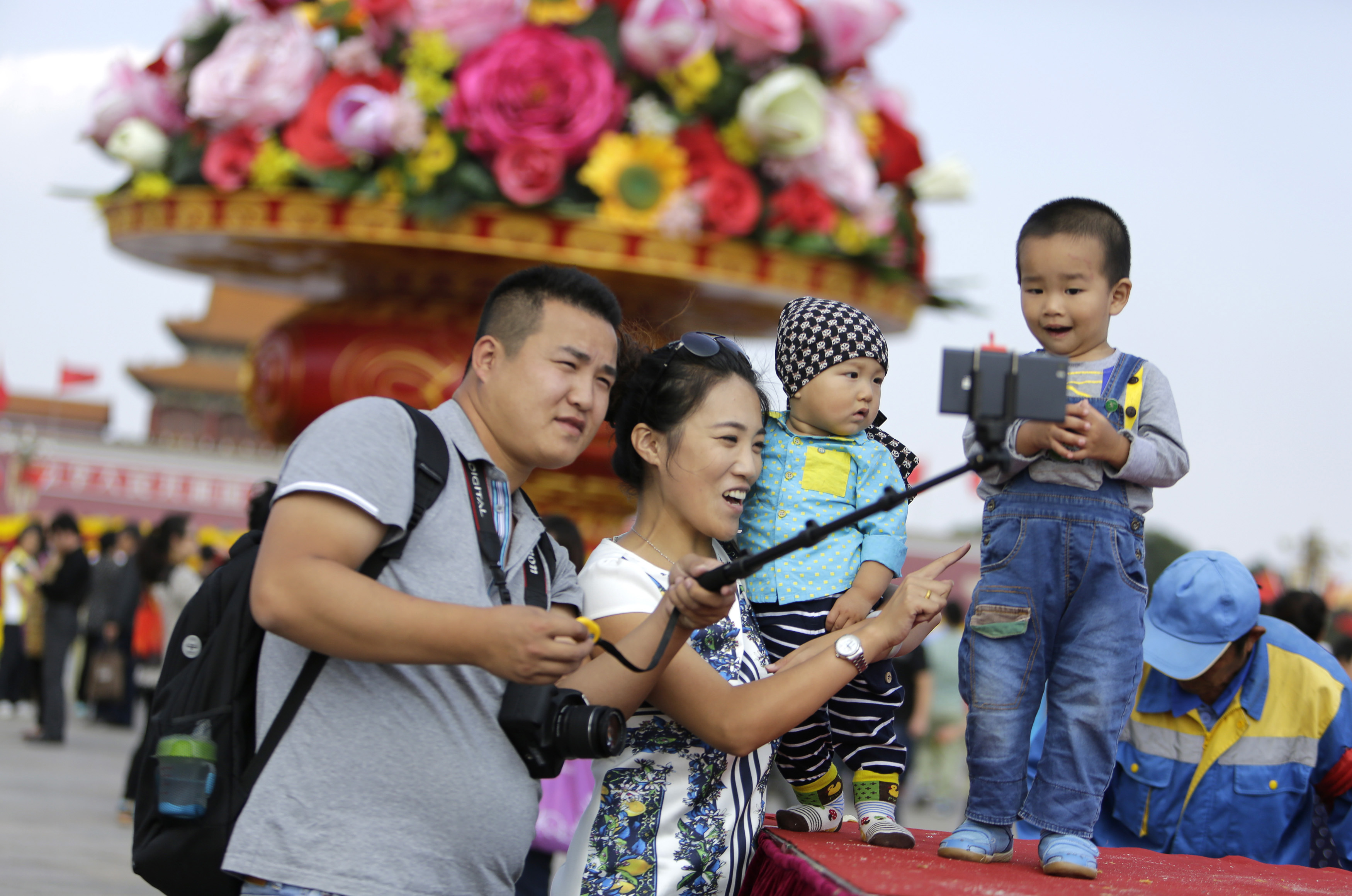 A family takes a "selfie" next to a boy in front of a giant basket of flowers on display at Tiananmen Square for the upcoming 65th National Day celebrations on Wednesday, in Beijing